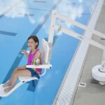 Accessible lift moving woman into swimming pool