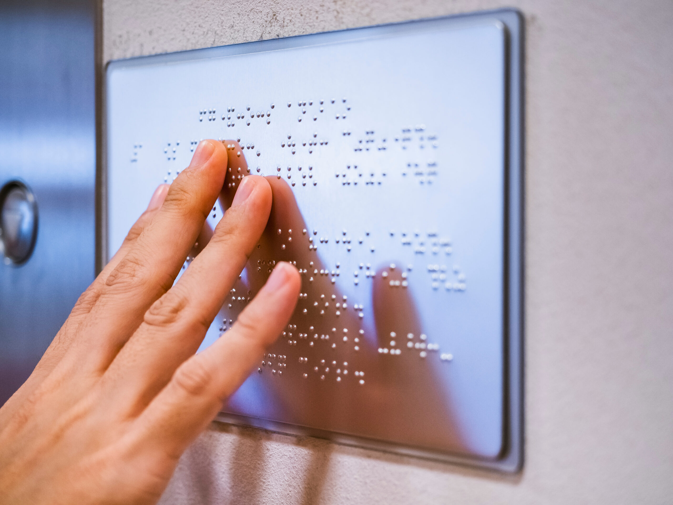 Hand on Braille sign on wall